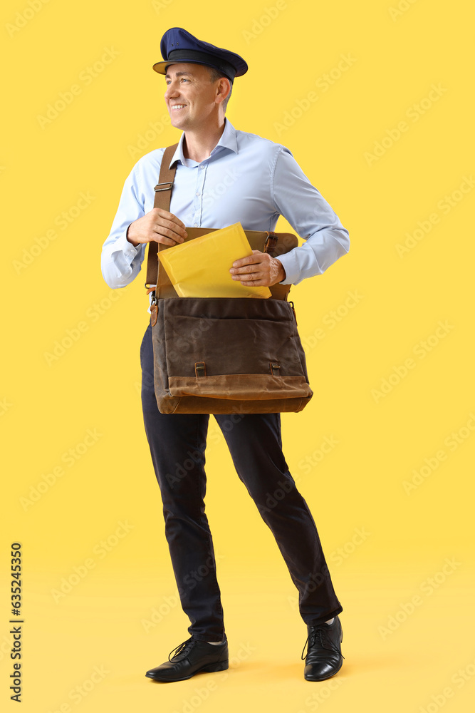 Mature postman with bag and envelope on yellow background