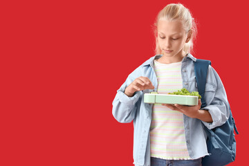 Poster - Happy girl with backpack and lunchbox on red background