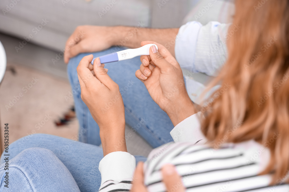 Happy young couple with pregnancy test at home, closeup