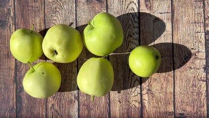 Canvas Print - Ripe apples on a wooden table on a bright sunny day. Harvesting fruit on the farm. The concept of growing apples