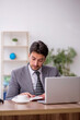 © Elnur - Young male employee reading book in the office