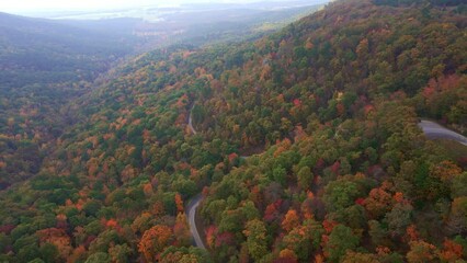 Wall Mural - Black suv driving on winding curved asphalt mountain country road through autumn forest and fall trees