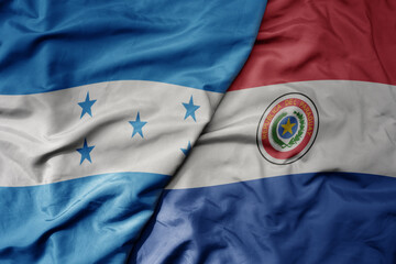 big waving realistic national colorful flag of honduras and national flag of paraguay .