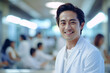 © NaphakStudio - Asian man doctor smiling after finishing work with a blurred hospital interior background.
