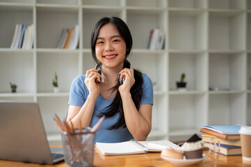 Wall Mural - A pretty Asian female college student sits at her study table at home.