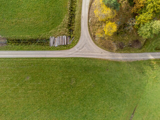 Wall Mural - Aerial view of deciduous forest, Swedish countryside in autumn. Colorful foliage, green fields and forest road seen from above, bird's eye view. Drone nature photography taken in Sweden in October.