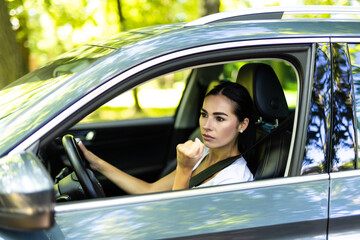 Wall Mural - Angry aggressive woman is clenching her fists and threatening from her car.