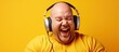 © HN Works - Overweight man in his 30s bald with headphones enjoying music and using phone on yellow background