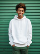 Sweatshirt mockup, African-American teenager wearing blank white hoodie stands in front of green wall looking and camera and smiling, teen apparel mockup with no print or label, kids fashion