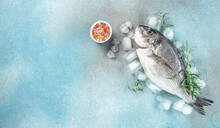 Raw Fresh Dorado Or Sea Bream On Ice Cubes On Blue Concrete Background. Long Banner Format. Top View