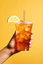 A Hand Holding Takeaway Plastic Cup Of Delicious Iced Lemon Tea Isolated On Yellow Background