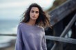 © JuanM - Multicultural young woman wearing a lavender sweater on the boardwalk of a coastal area. Generative AI.