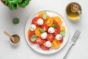 Wall Mural - Appetizing Italian caprese salad. Tomatoes mozzarella basil salad close-up view on white background