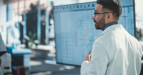 Leinwandbilder - Senior Robotics Engineer Giving Presentation in front Of Television Set With Ai Robot Blueprint. Automation Specialist Explaining Technological Specs To Assembly Line Workers In Startup Company.
