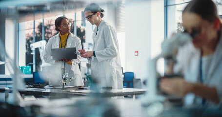 Aufkleber - Diverse Young Group of Engineers Working in a Startup Lab. Female Specialist Checking on Electronic Circuit Using Microscope While Two Project Managers Discuss Manufacturing Using Laptop Computer