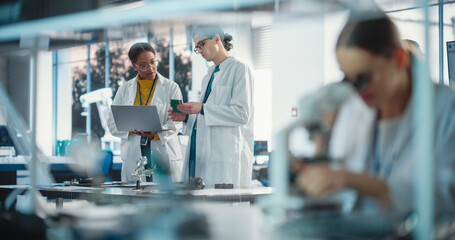 diverse young group of engineers working in a startup lab. two project managers discuss manufacturin