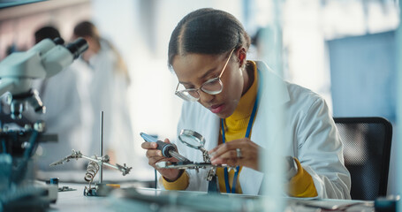 Aufkleber - Portrait of Black Female Lab Specialist Carefully Soldering a Circuit Board in a Manufacturing Industrial Company. Professional Woman in Lab Coat Working on the Latest Technological Project