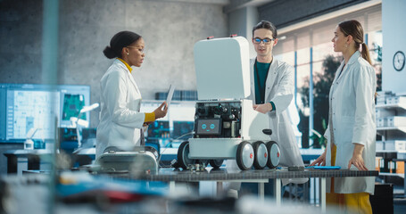 Poster - Team of Industrial Specialists Working on Mobile Robot, Using a Laptop. Young Male and Female Engineers in a Lab Discussing an Automated AI Robotic Delivery Assistant, Brainstorming New Ideas