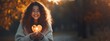 © irissca - Mental health in Autumn season. Fall happy mood, positive emotions as a remedy for autumn depression. Autumn photo of happy beautiful girl holding glow heart shape in hands.