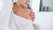Woman in bathrobe applying moisturizer cream on shoulder