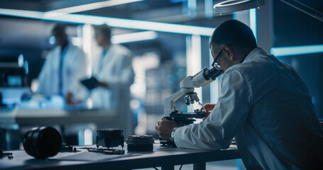 Poster - Scientist Using Modern Digital Microscope in a Research and Development Facility. On Blurred Background Diverse Team of Industrial Specialists Working on Remotely Controlled Mobility Robot