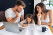 © DusanJelicic - Young parents teach their daughter to write, helping her with her homework, untidy desk and laptop. Concept happy healthy family