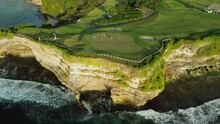 Drone Footage Of A Group Of People Playing Golf At A Country Club Perched On A Cliff By The Ocean. Green Golf Course On The Coast, People Play Golf.