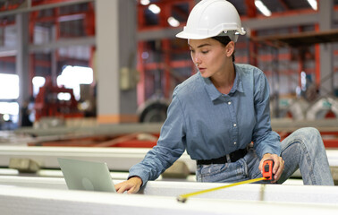 Wall Mural - Manufacturing supervisor wears safety helmet examining heavy metal production. Factory worker or manager control product quality in workshop. Female technician working in maintenance engineering