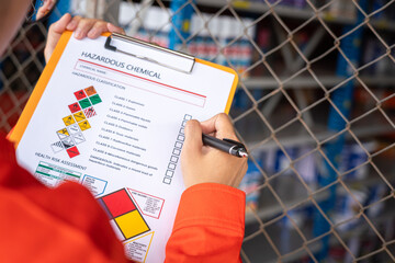 Wall Mural - a worker is checking on the hazardous chemical material information form with background of chemical