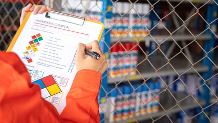 Wall Mural - a worker is checking on the hazardous chemical material information form with background of chemical