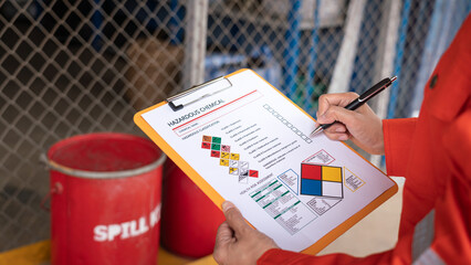 Wall Mural - action of safety officer is checking chemical hazard material form for correct the oil spill kit whi