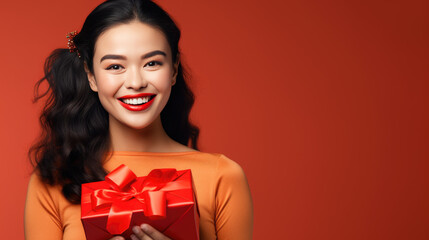 Wall Mural - Happy smiling woman holding gift box over red background