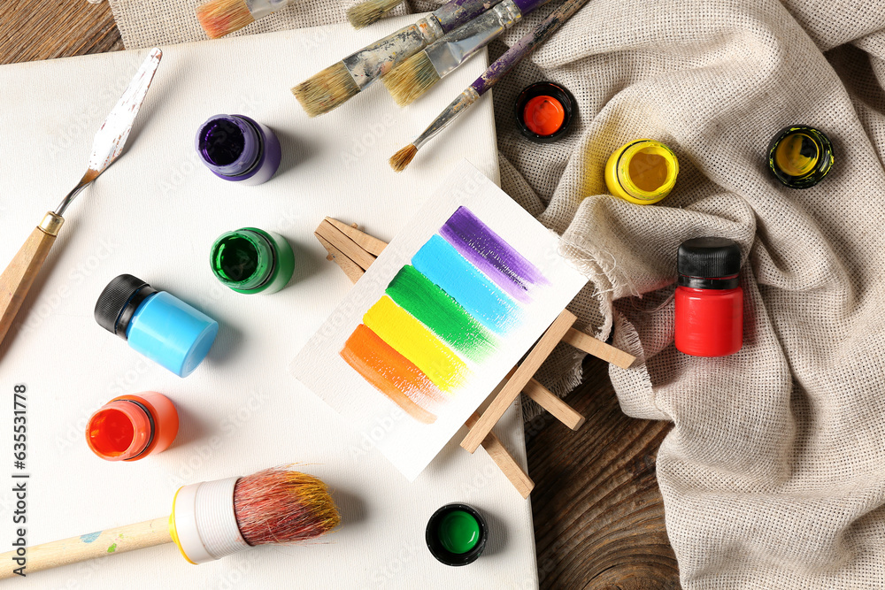 Canvas with brushes, paints and cloth on brown wooden table