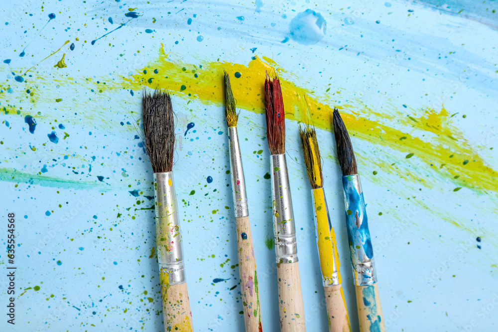 Artist's brushes with paints on blue background