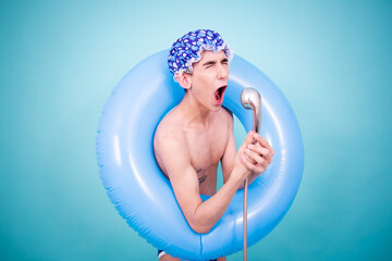 Wall Mural - Young attractive guy washes in the shower. Blue background.