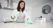 Happy woman, housekeeper and cleaning kitchen table with spray bottle, detergent or bacteria and germ removal at home. Female person maid or cleaner wiping surface with cloth in hygiene or sanitise