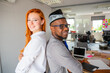 © Media Lens King - Two colleagues posing smiling in the office back to back, corporate life