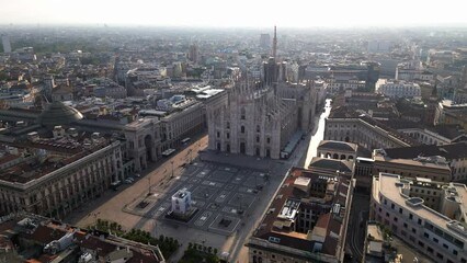 Wall Mural - Europe, Italy, Milan - Aerial view of Piazza Duomo, gothic Cathedral in downtown center city. Drone aerial view of the gallery and rooftops during sunrise - Duomo Unesco Heritage sightseeing 