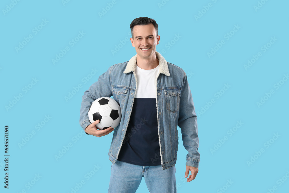 Young man with soccer ball on blue background