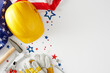 © Goncharuk film - Concept for a joyful Labor Day celebration. Top view photo of american flag, yellow hard hat, tools, safety gloves, event confetti on white background with empty space for promo or message