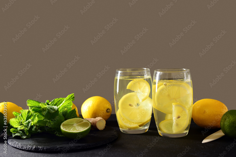 Glasses of tasty lemonade with mint and lime on black table