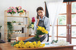 © Katcha - Female florist in apron using smartphone to talking receive order with customer while holding yellow