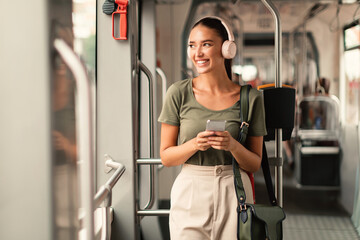 Wall Mural - Passenger Woman Standing in Tram, Listening Music Online On Phone