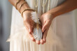 © Jasmina - Woman with boho jewellery holding a feather in her hands close up