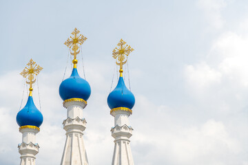 Close-up view of blue cupolas with golden crosses of Russian Orthodox Nativity Church at Putinki in Moscow against cloudy sky in a summer day. Copy space for your text. Religious architecture theme.