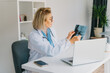 © okrasiuk - Female doctor makes online video call consult patient on laptop. Middle aged woman therapist videoconferencing for domestic health treatment. Telemedicine concept. Online remote medical appointment