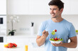 Man with vegetable salad at home kitchen