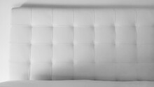 Soft Headboard. Upholstery For Furniture Made Of Genuine Or Artificial Leather And Quilted Fabric. Soft Headboard Against A Light Wall. Black And White Monochrome Photo