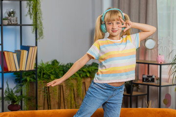 Portrait of happy overjoyed toddler girl kid in wireless headphones relaxing at home room choosing listening favorite energetic disco dancing music. Children weekends leisure activities. Lifestyles