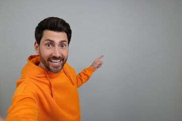 Poster - Smiling man taking selfie on grey background, space for text